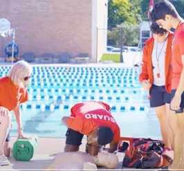 lifeguards practicing CPR on pool deck 